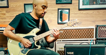 male musician playing electric guitar in front of VOX amplifiers