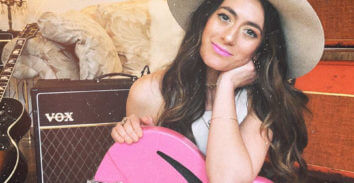 woman with pink electric guitar in front of VOX amplifier