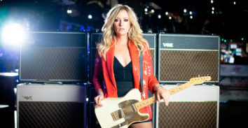 woman with electric guitar in front of VOX amplifiers