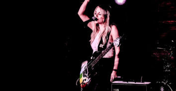 female musician playing electric guitar beside VOX amplifier in concert