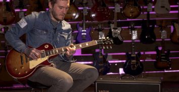 man in music store playing electric guitar beside VOX amplifier