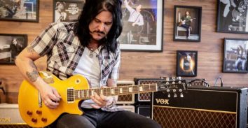 male musician playing yellow electric guitar in front of VOX amplifier
