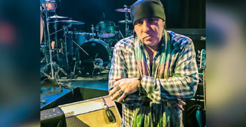 male musician standing beside VOX amplifier on stage