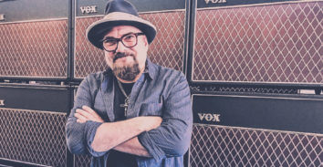 man with crossed arms standing in front of multiple VOX amplifiers